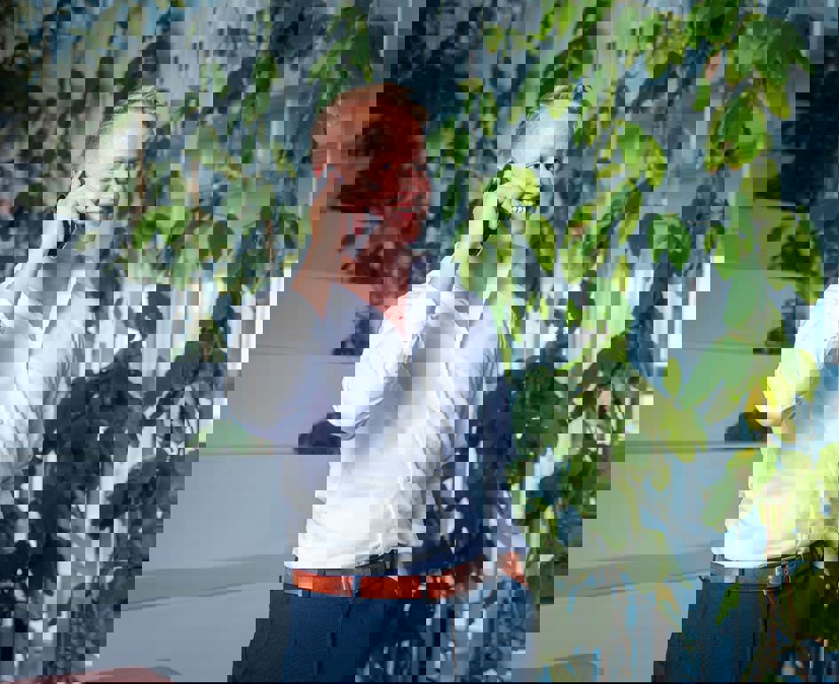 Man telefoneert en er staat een plant op de achtergrond