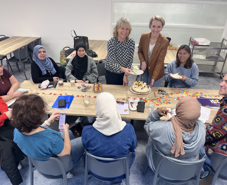 Miranda Zwart en Anja Witte delen taart uit aan deelnemers van Het Taalhuis